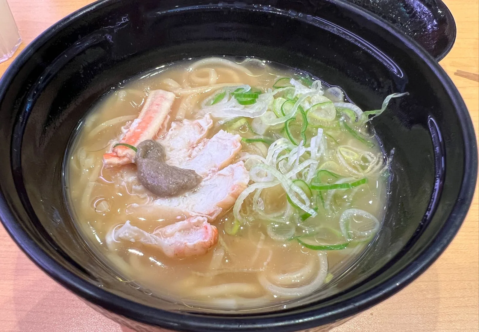 黒い丼に盛られた黄金色スープのかにみそラーメン